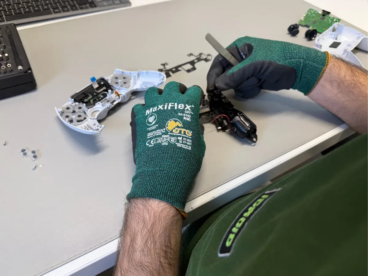 Tehnician demontează un controller alb, cu carcasa deschisă și placa scoasă alături