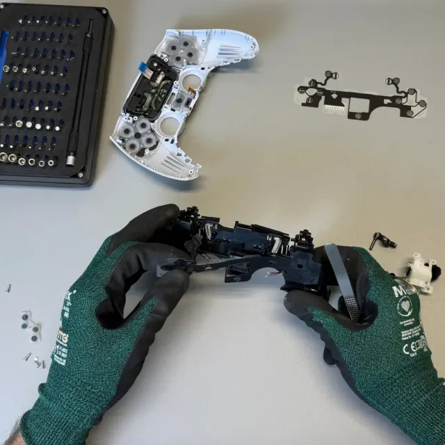 Tehnician desface un controller DualSense PS5 pe bancul de lucru